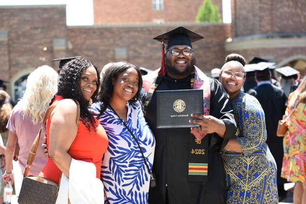 A graduate poses for a celebration photo with his family after Commencement